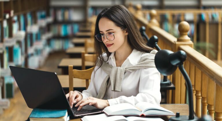 Student working with a laptop and books in a library