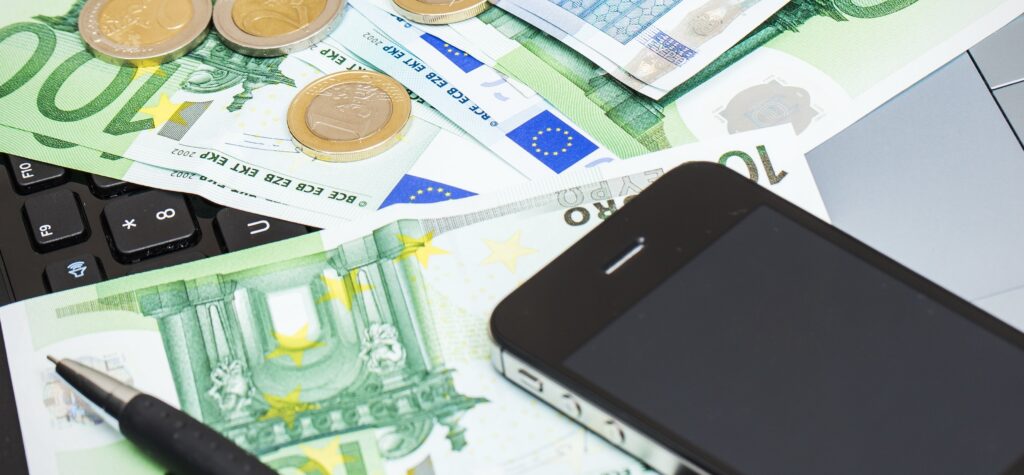 Laptop, mobile phone, and cash on a table