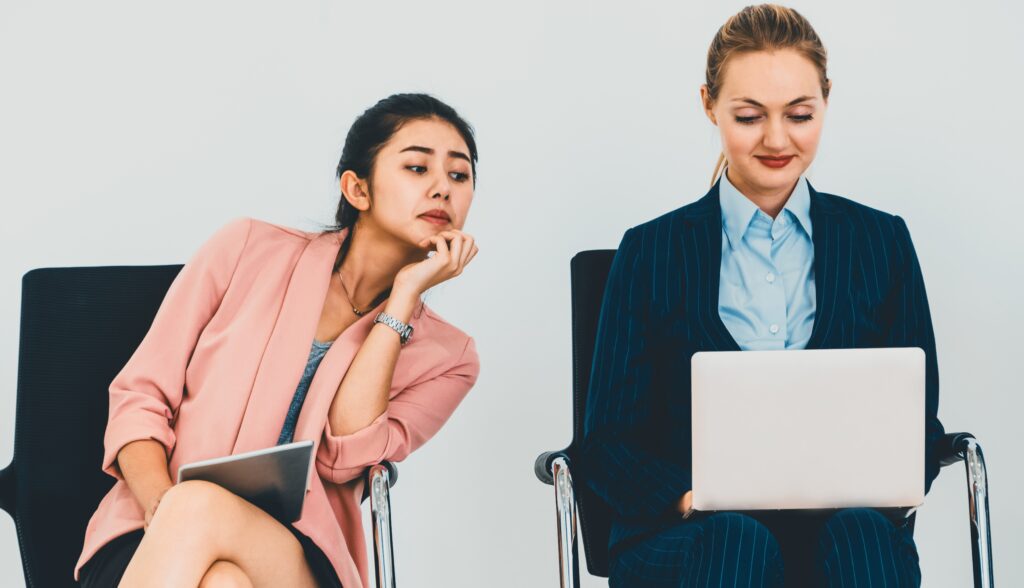 Businesswoman looking at another person’s laptop screen