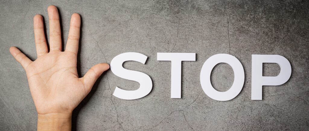 Word stop with a child’s hand on a dark wall