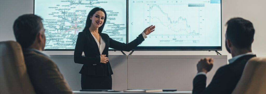 Three people discussing beside a screen in an office